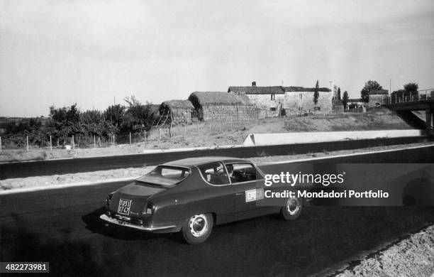 The car of the Epoca magazine reporters running across a still closed stretch of the Autostrada del Sole between Valdarno and Orvieto. Italy, 1964