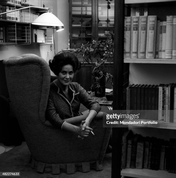 Italian actress Alida Valli smoking a cigarette seated on an armchair. Italy, 1960s