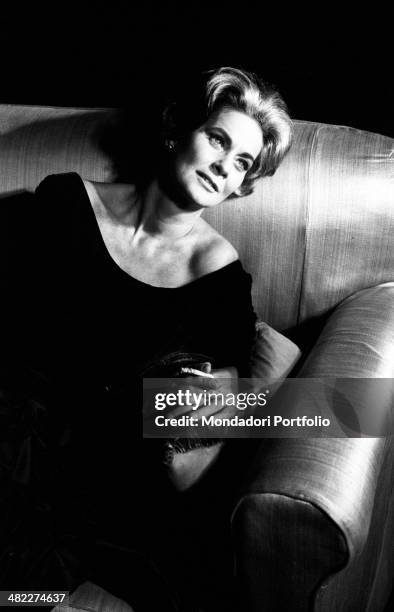 Italian actress Alida Valli smoking a cigarette seated on a sofa. Italy, 1960s