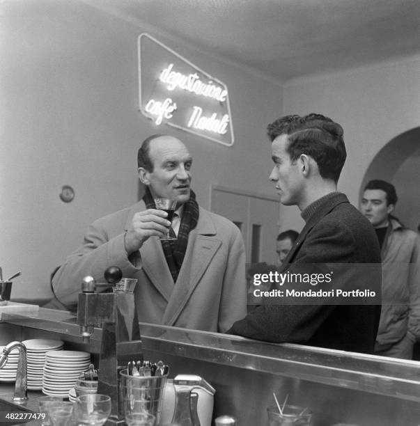 Italian football player Mario Corso talking to Italian former football player Andrea Milani at the counter of a bar in the district San Michele Exra...