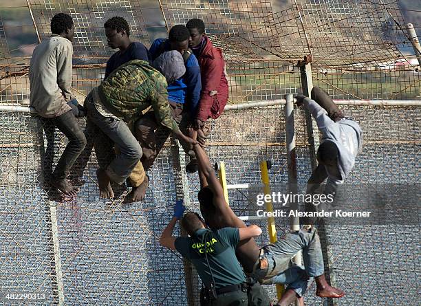 Guardia Civil Officer tries to help a dehydrated African migrant, after the attempt to scale the fence at the border between Morocco and the North...