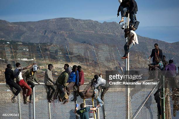 Guardia Civil Officer tries to help a dehydrated African migrant, after the attempt to scale the fence at the border between Morocco and the North...