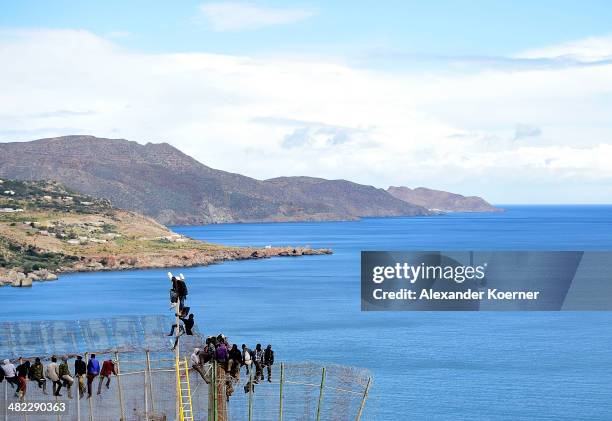 African migrants attempt to scale the fence at the border between Morocco and the North African Spanish enclave of Melilla, on April 3 in Melilla,...