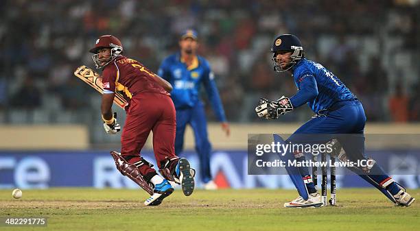 Dwayne Bravo of the West Indies hits the ball towards the boundary, as Kumar Sangakkara of Sri Lanka looks on during the ICC World Twenty20...