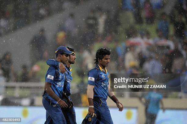 Sri Lankan cricketer Nuwan Kulasekara walks off the field with teammates as heavy rain falls during the ICC World Twenty20 cricket tournament first...