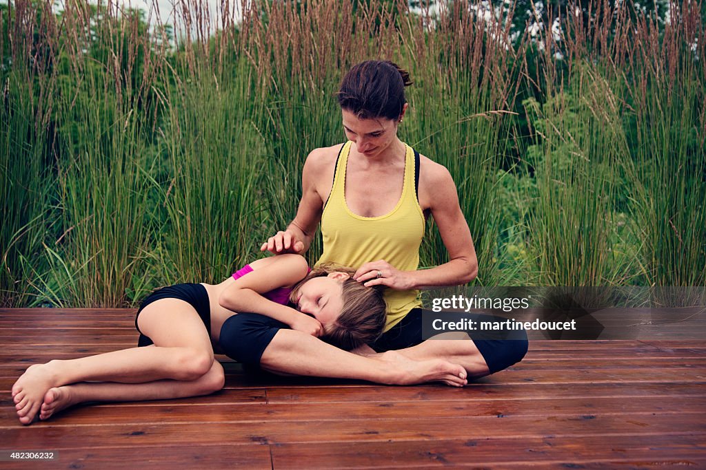 Tierno momento entre la Madre e hija haciendo yoga en la naturaleza.