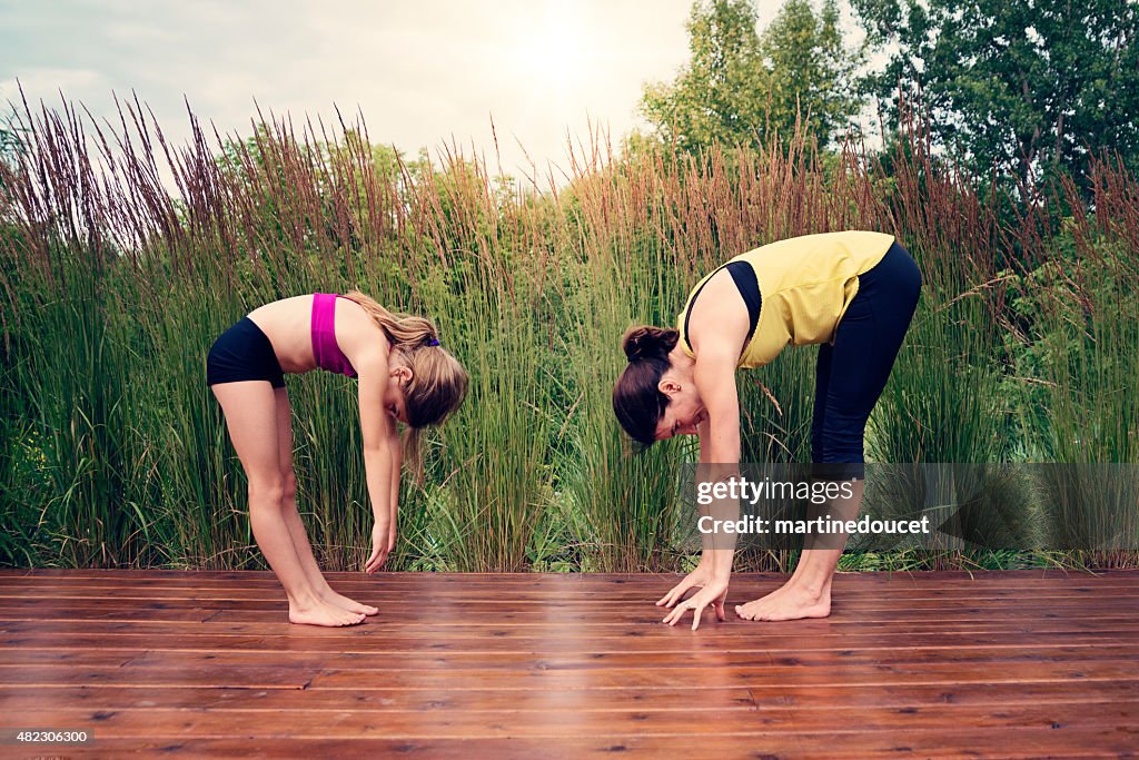 Madre e hija haciendo yoga en verano naturaleza.