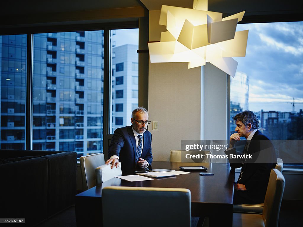 Businessmen sitting in meeting in hotel suite