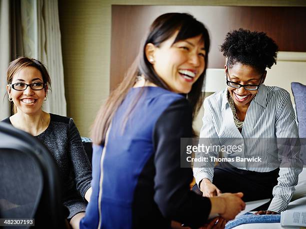 three smiling businesswomen working in hotel suite - leanincollection stock pictures, royalty-free photos & images