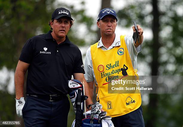 Phil Mickelson of the United States talks with his caddy Jim Mackay during round one of the Shell Houston Open at the Golf Club of Houston on April...