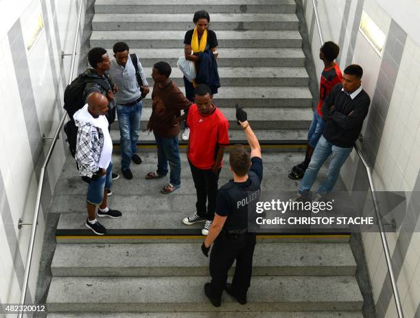 Refugees wait near the first registration point of the German federation police in Rosenheim, southern Germany, on July 29, 2015. Hundreds of...