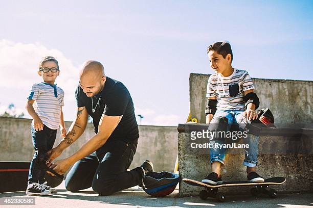 father and sons at skate park - kneepad stock pictures, royalty-free photos & images