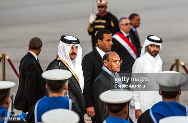 Qatar's Emir Sheikh Tamim bin Hamad Al Thani and Tunisian President Moncef Marzouki walk past an honor guard during an official welcoming ceremony at...