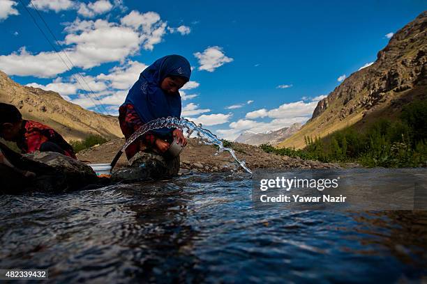 Girl washes dishes on the Indus river flowing towards Pakistan administered Kashmir on July 30, 2015 in Drass, 142 km east of Srinagar the summer...