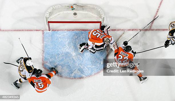 Tye McGinn, Luke Schenn and Steve Mason of the Philadelphia Flyers battle for the puck in their crease against Milan Lucic and David Krejci of the...