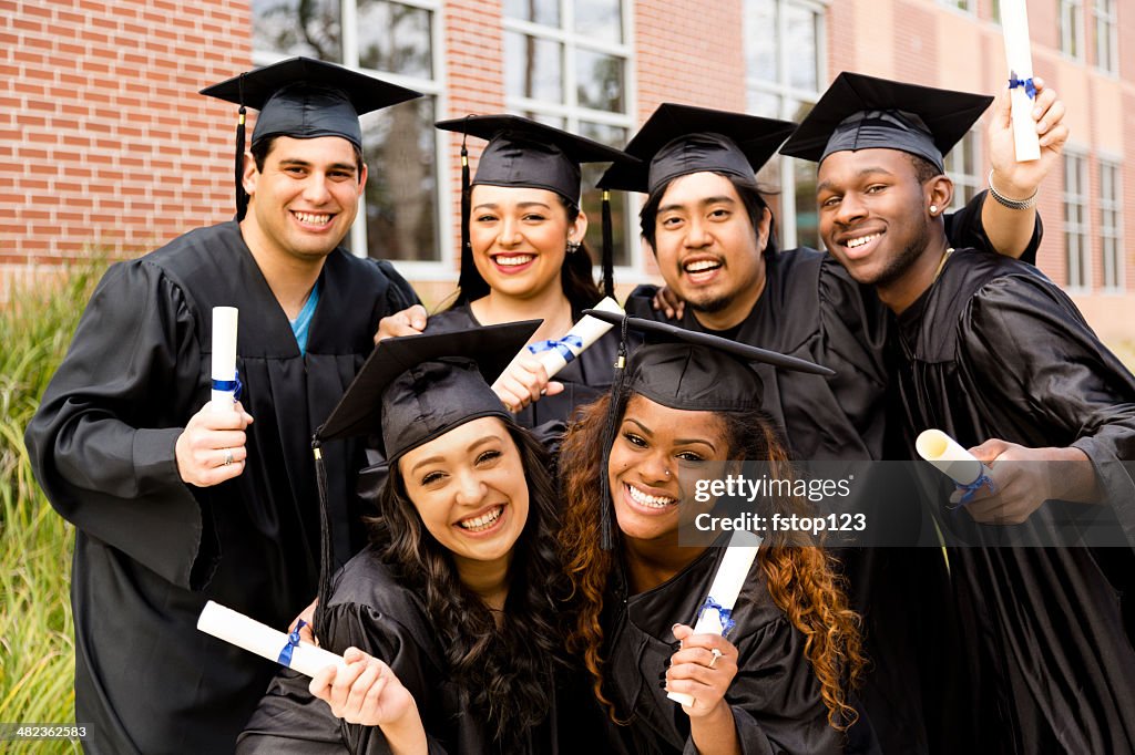 Education: Multi-ethnic friends excitedly hold diplomas after college graduation.