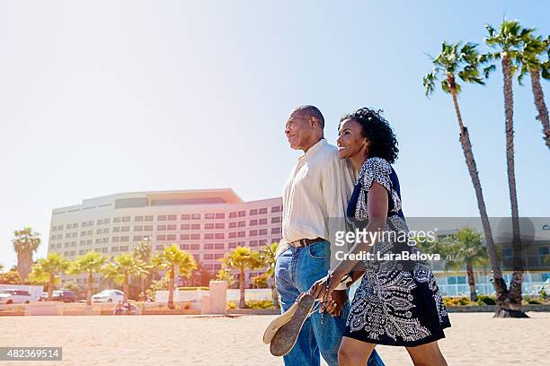 afrikanische älteres paar in der liebe zu fuß am strand - holiday tourist usa stock-fotos und bilder
