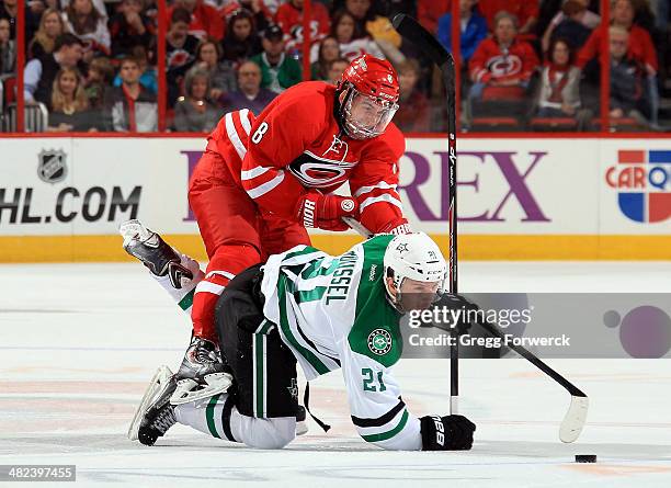 Andrei Loktionov of the Carolina Hurricanes takes the puck away from Antoine Roussel of the Dallas Stars as he falls to the ice during their NHL game...