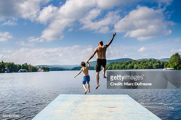 father and son jumping in lake - lake stock pictures, royalty-free photos & images