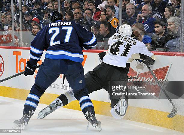Robert Bortuzzo of the Pittsburgh Penguins goes flying into the boards after getting tangled up with Eric Tangradi of the Winnipeg Jets during first...