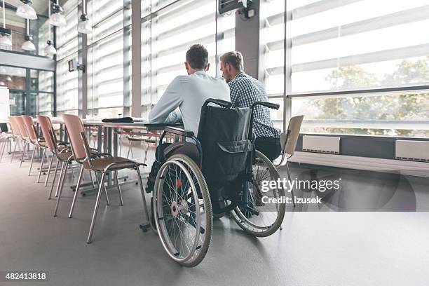disabled businessman working with his colleague in an office - disability insurance stock pictures, royalty-free photos & images