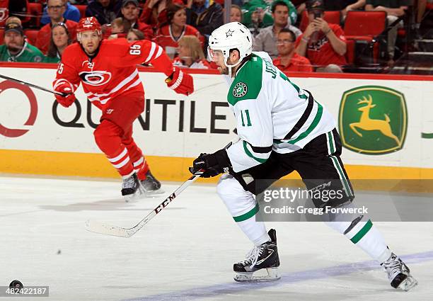 Dustin Jeffrey of the Dallas Stars moves the puck into the attacking zone as Ron Hainsey of the Carolina Hurricanes looks on during their NHL game at...