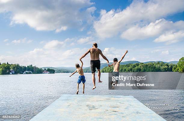 father and sons jumping in lake - jumping into lake stock pictures, royalty-free photos & images