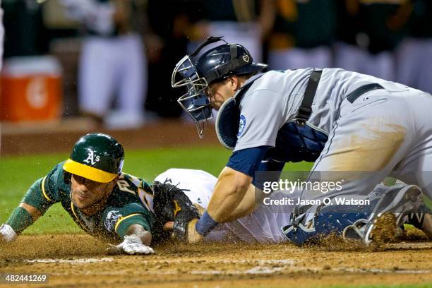 Sam Fuld of the Oakland Athletics is tagged out at home plate by Mike Zunino of the Seattle Mariners attempting to extend a triple into an in the...