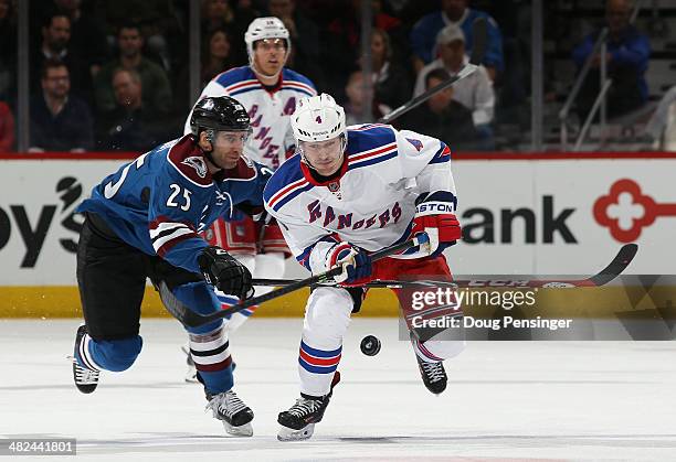 Raphael Diaz of the New York Rangers and Maxime Talbot of the Colorado Avalanche pursue the puck at Pepsi Center on April 3, 2014 in Denver,...