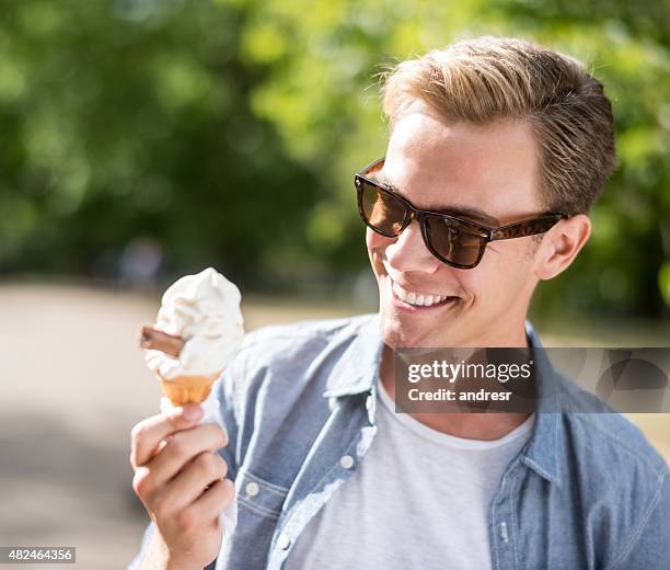 man eating an ice cream at the park - alleen één man stockfoto's en -beelden