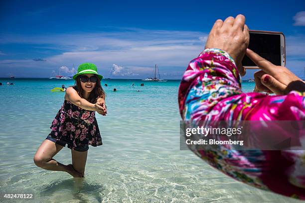 Chinese tourist poses for a photograph in the sea at White Beach in Boracay, the Philippines, on Wednesday, July 29, 2015. The Philippines, an...