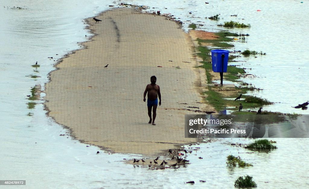 A devotee walks at a road submerged around with flooded...