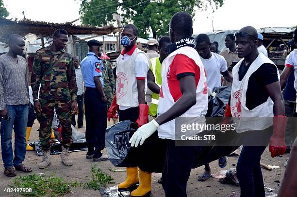 Nigerian Red-Cross workers carry a body away from the scene of an Improvised Explosive Device blast at Gomboru market in Maiduguri, Borno State in...