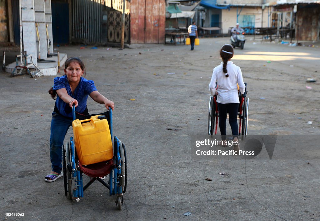 Palestinian girl pushed the wheel chair carrying can that...