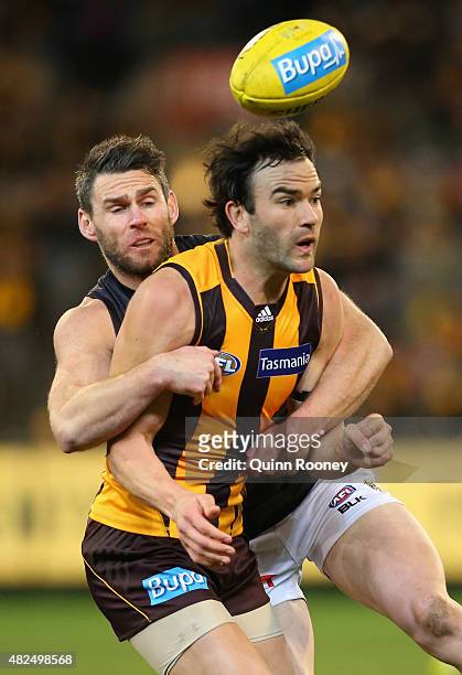 Jordan Lewis of the Hawks handballs whilst being tackled by Chris Newman of the Tigers during the round 18 AFL match between the Hawthorn Hawks and...