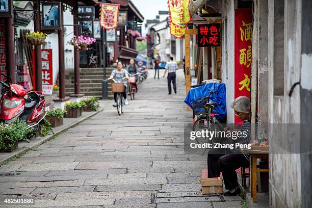 An old woman sits on the Cangqiao street, doing traditional knitting and weaving. Cangqiao street is a famous ancient street popular in tourists....