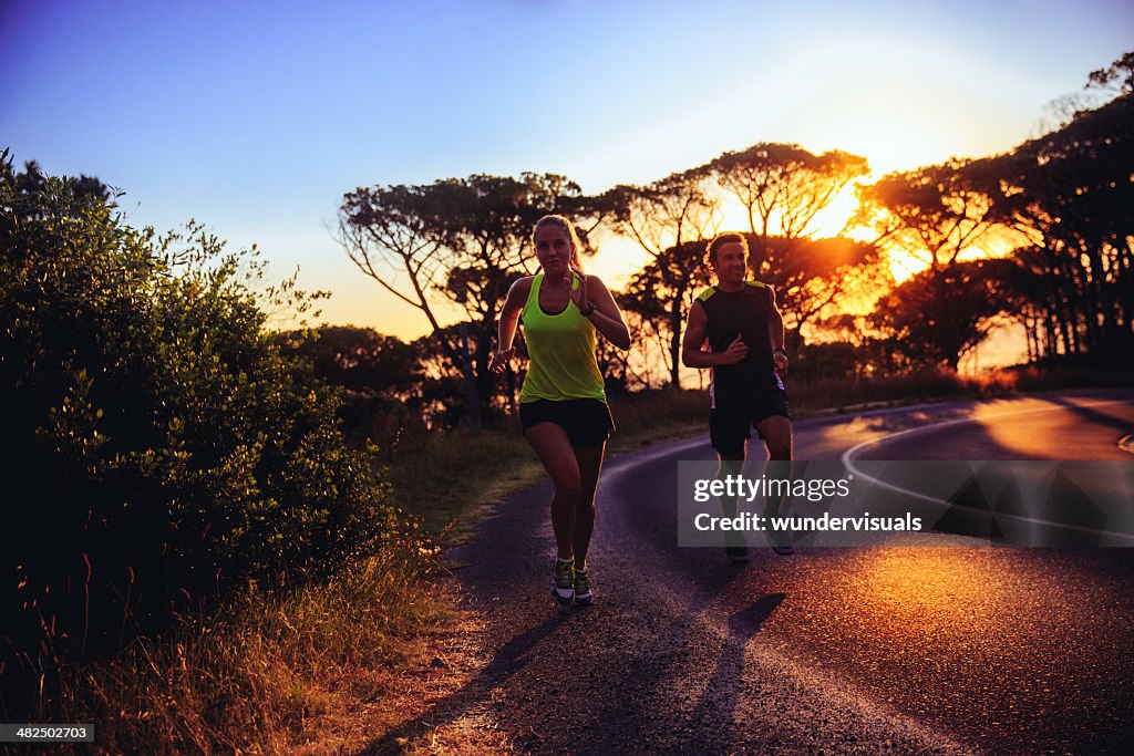 Young couple running together at sunrise
