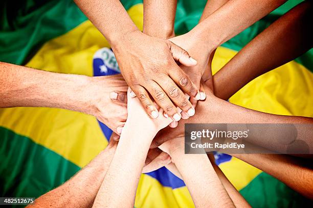 diverse mani misto pile sulla bandiera del brasile deposito in pegno fedeltà - brazilian flag foto e immagini stock