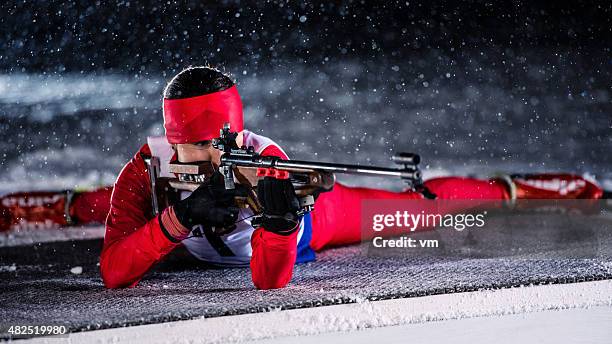 female shooting at biathlon training at night - schietsport stockfoto's en -beelden