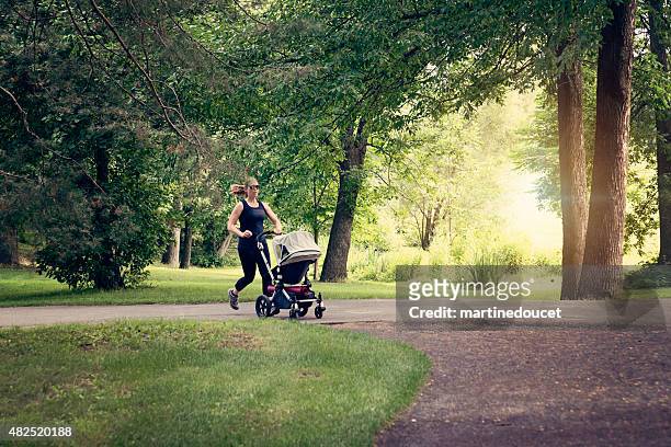 new mother jogging with stroller in public park. - jogging stroller stockfoto's en -beelden