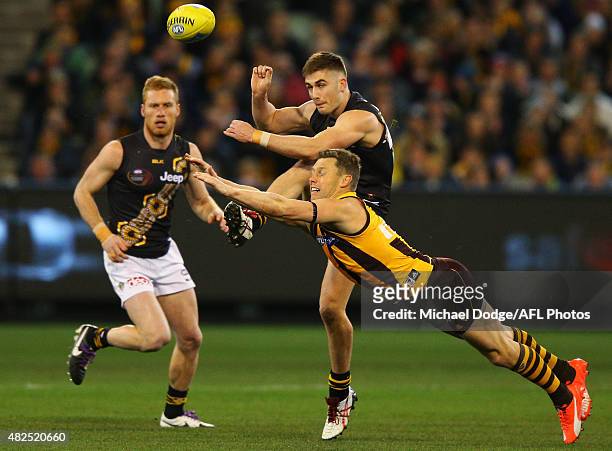 Sam Mitchell of the Hawks smothers the kick of Kane Lambert of the Tigers during the round 18 AFL match between the Hawthorn Hawks and the Richmond...