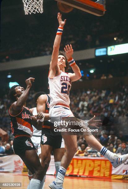 Doug Collins of the Philadelphia 76ers goes up to shoot over T.R. Dunn of the Portland Trail Blazers during an NBA basketball game circa 1979 at The...