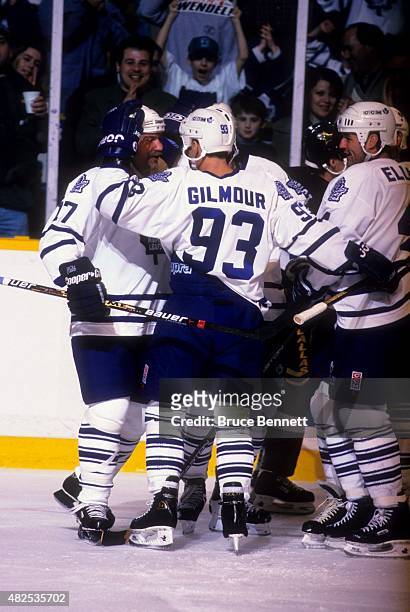 Doug Gilmour and Dave Ellett of the Toronto Maple Leafs celebrate with Wendel Clark after Clark scored during their game agaisnt the Dallas Stars on...