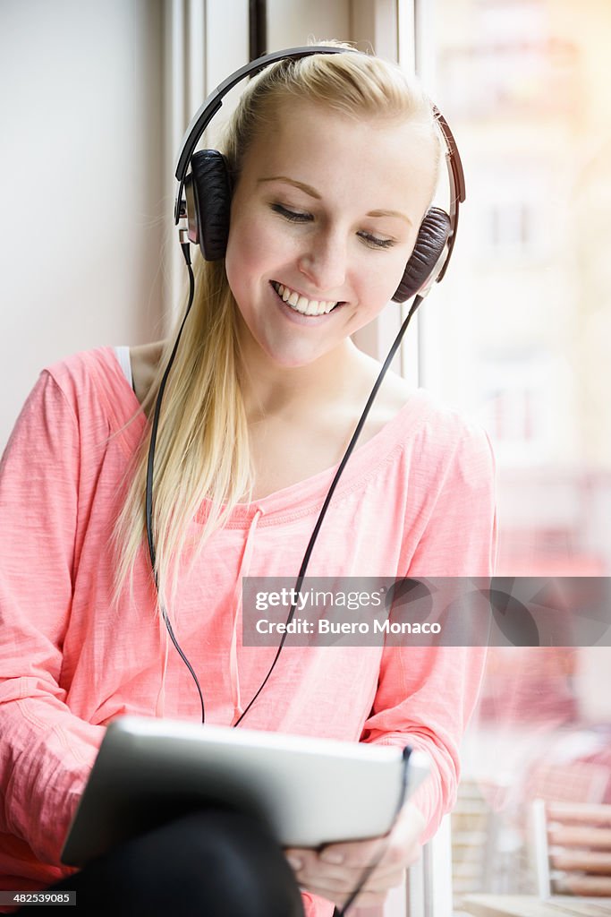 Woman listening to headphones in cafe,using tablet