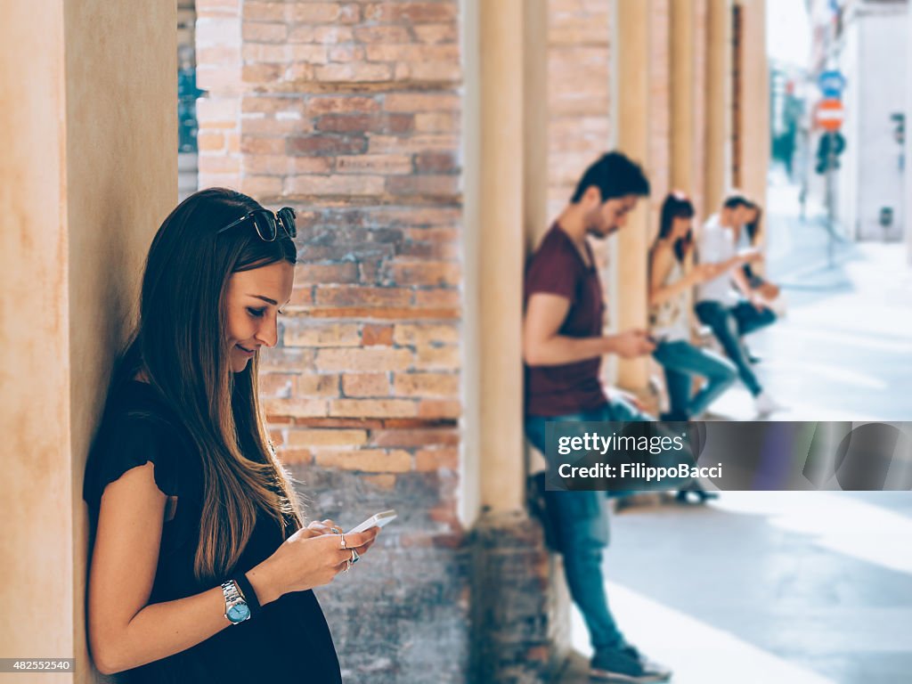 Giovani amici utilizzando telefoni cellulari all'aperto