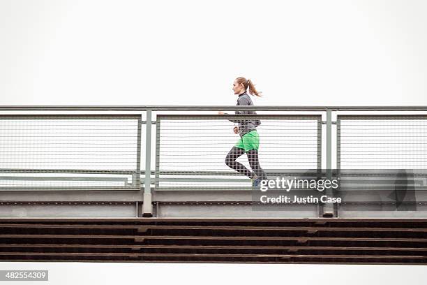 sporty woman jogging on an urban bridge - corredora de footing fotografías e imágenes de stock