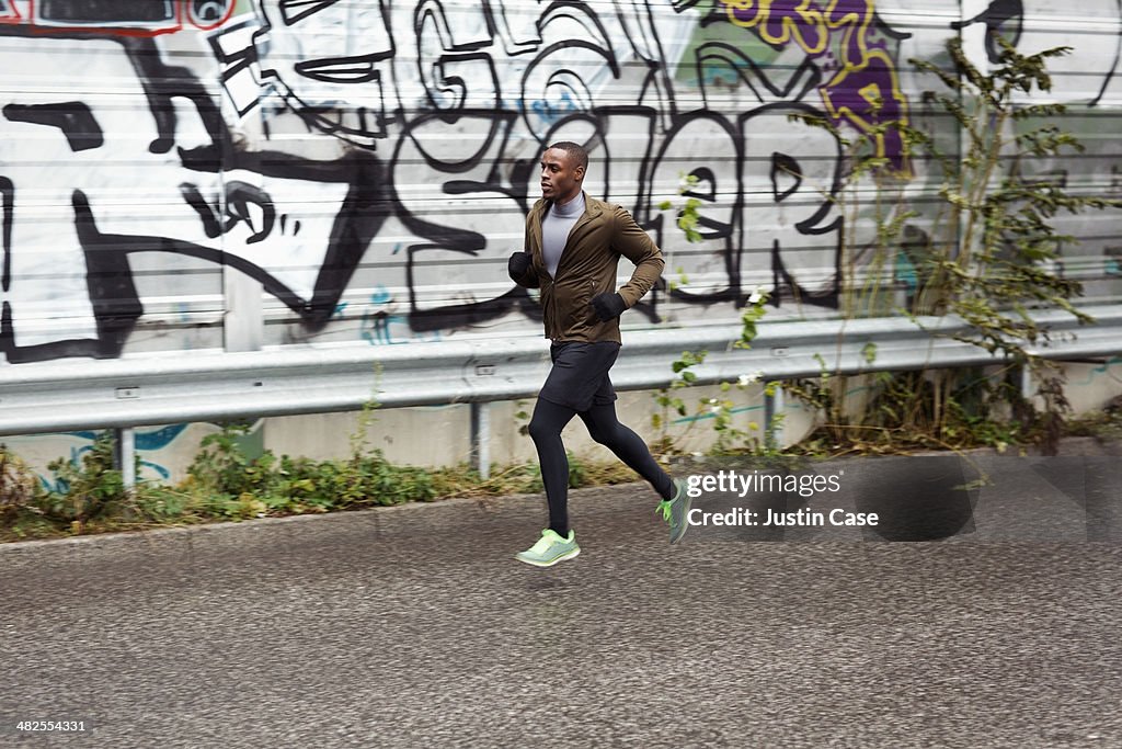 Sporty man jogging fast on an urban street