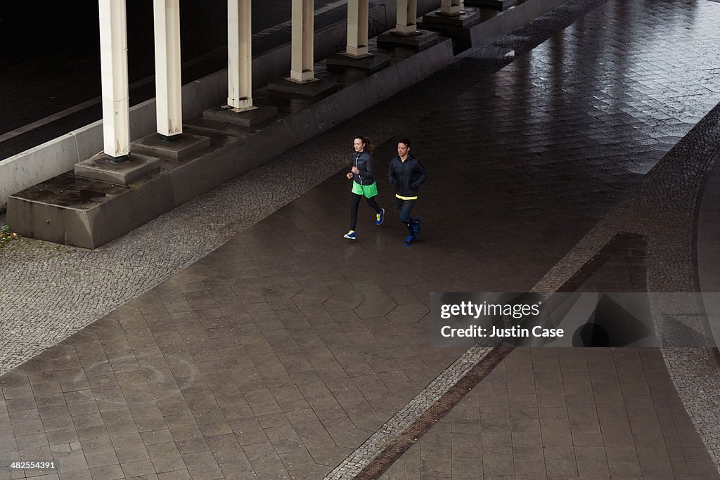 Couple of young sporty people running in the city