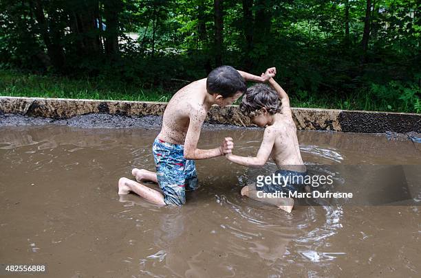 two kids fighting in mud - wrestling stockfoto's en -beelden