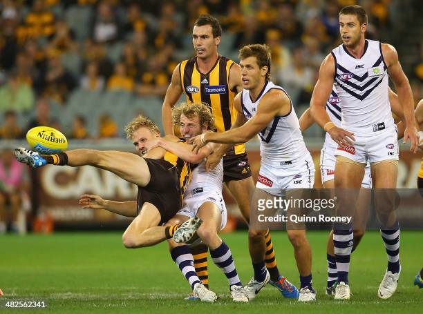 Will Langford of the Hawks kicks whilst being tackled by David Mundy of the Dockers during the round three AFL match between the Hawthorn Hawks and...